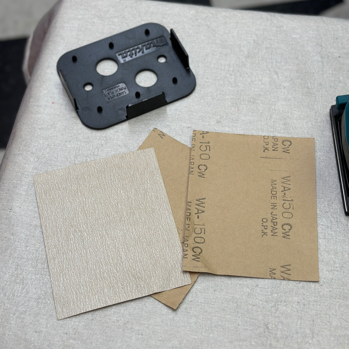 Makita BO4556 finishing sander with dust bag, punch plate, and sanding sheets
