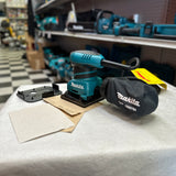 Renewed Makita BO4556 sander with included dust bag, punch plate, and sanding sheets
